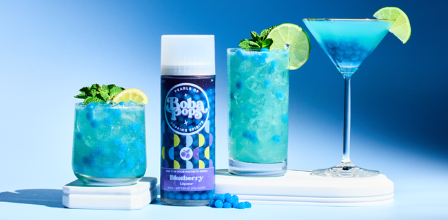 Blue cocktail with lime garnish, Boba POPS blueberry flavor, and a blue background