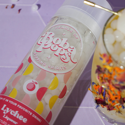 Bob Pops lychee liqueur bottle with a colorful drink in the background